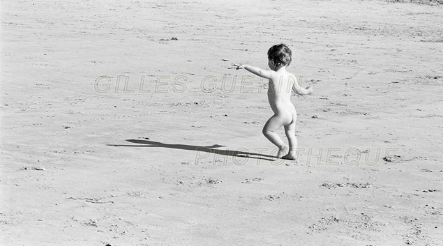 Silhouette d'un enfant de deux ans nu et courant sur la plage