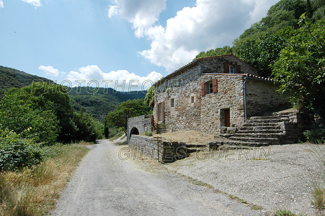 Petite vallée verte et maison cévenole traditionnelle restaurée en bordure d'un petit village médiéval