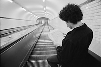 Métro parisien 1979 - Un jeune homme dans l'escalier mécanique lisant les annonces du journal