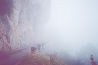Petite route dans le brouillard et au pied d'une falaise