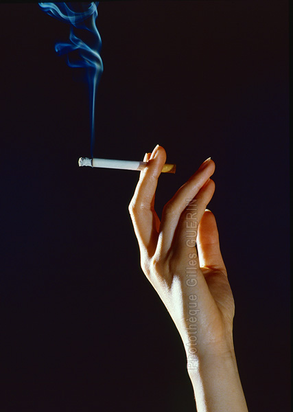Main de femme avec cigarette et volutes de fume