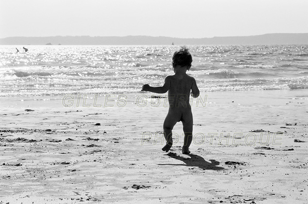 Silhouette en contrejour d'un enfant de 2 ans sur une plage et se dirigeant vers la mer
